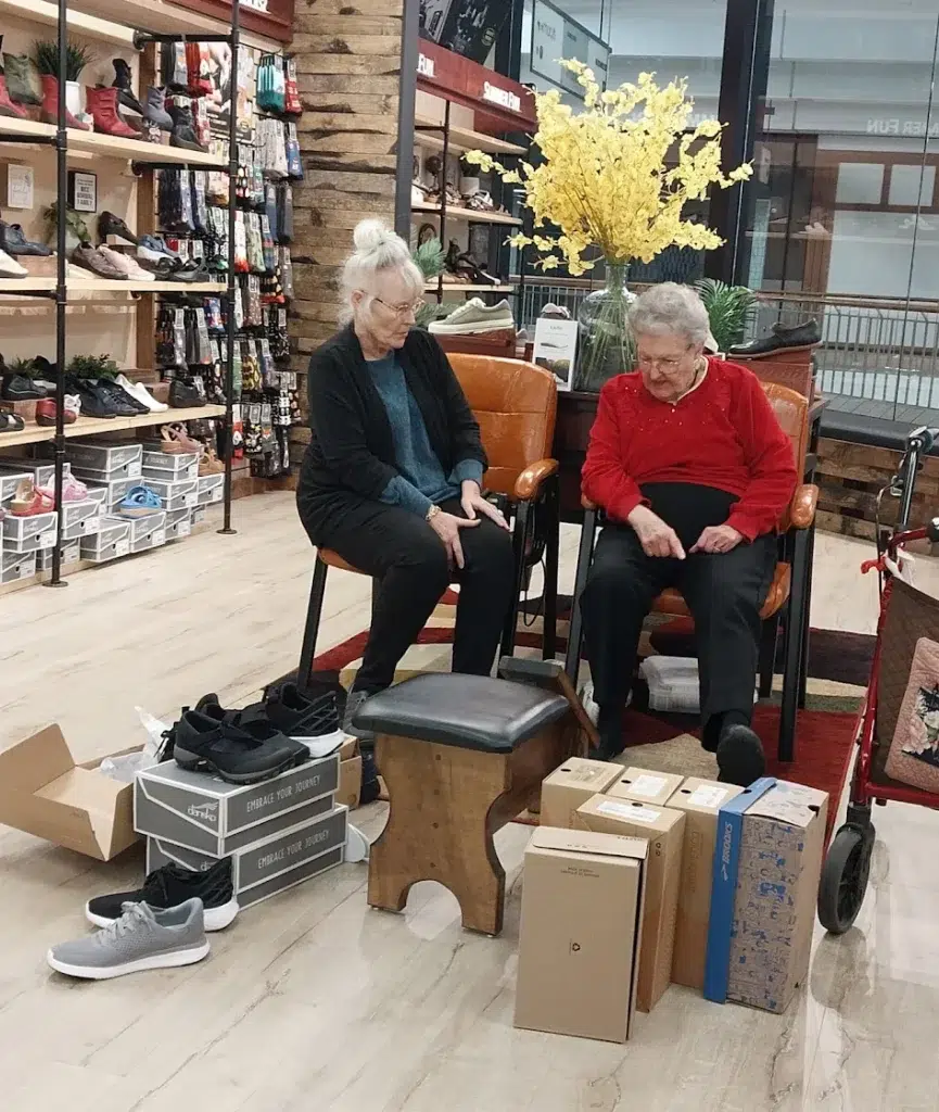 Two customers standing together inside a Beck’s Shoes store in Medford, smiling and trying on footwear.