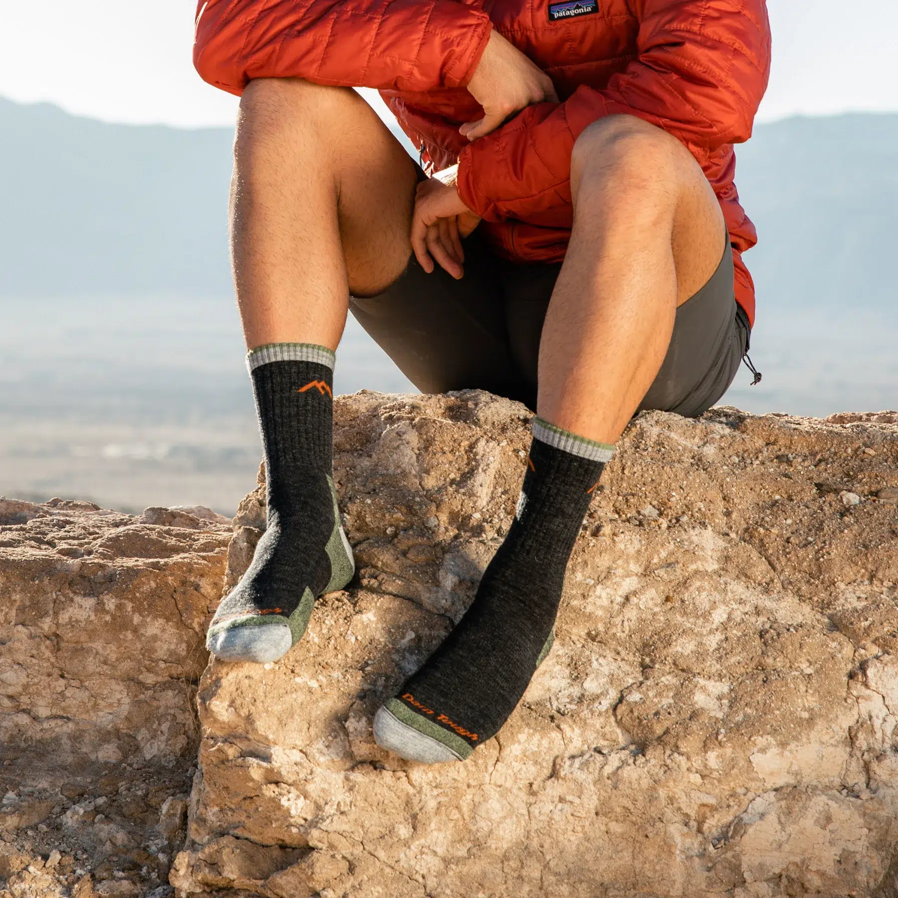 Man sitting on rock wearing Darn Tough midweight micro crew socks outdoors