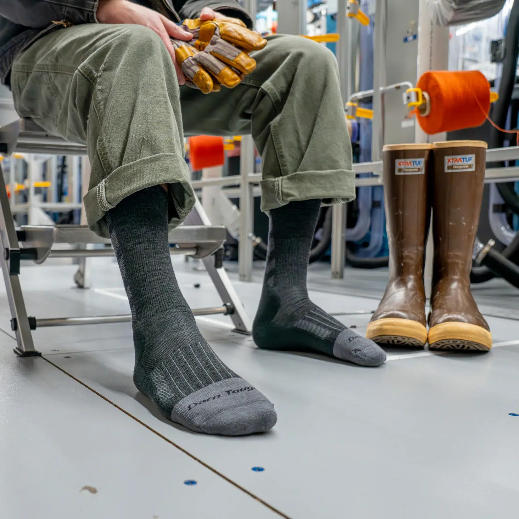 Man sitting on bench in locker room wearing Darn Tough socks with work boots