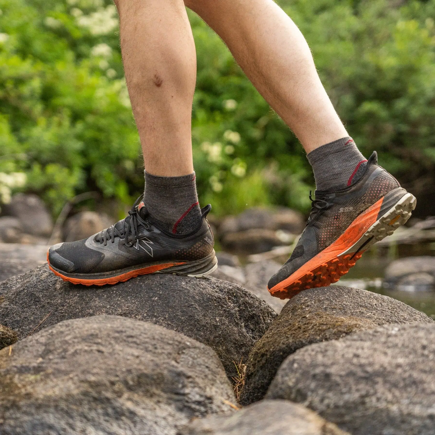 Man stepping across rocks wearing Darn Tough light hike quarter socks with trail shoes