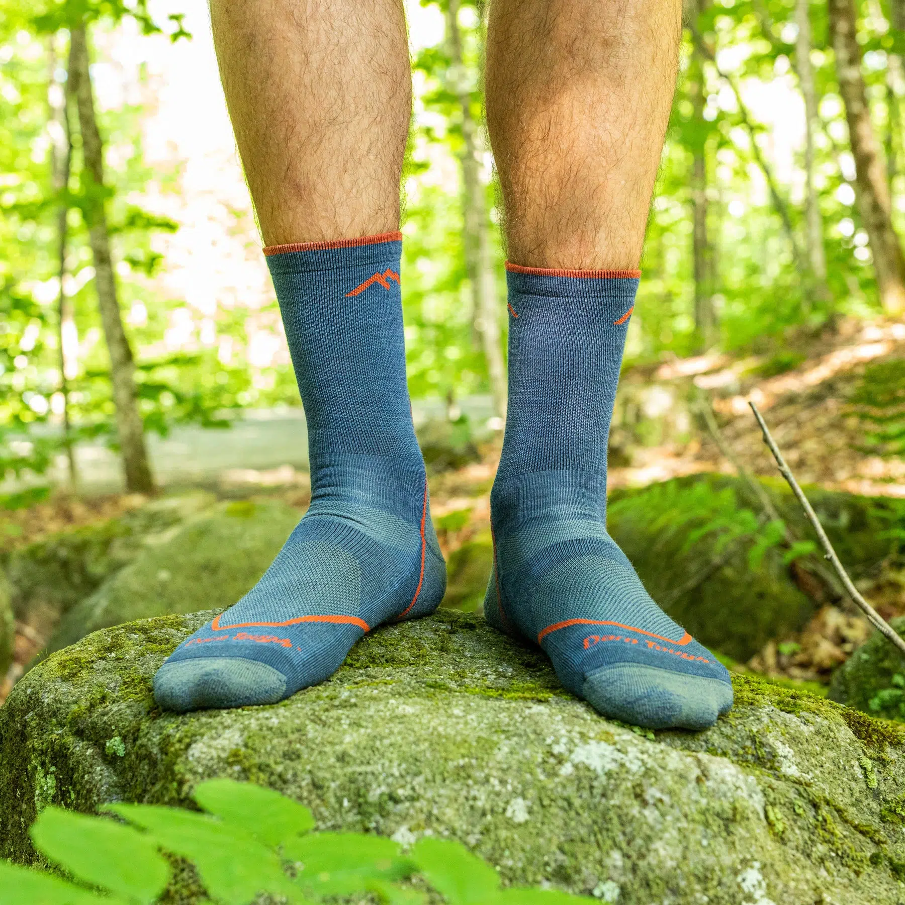 Man standing on mossy rock wearing Darn Tough light hike micro crew socks outdoors