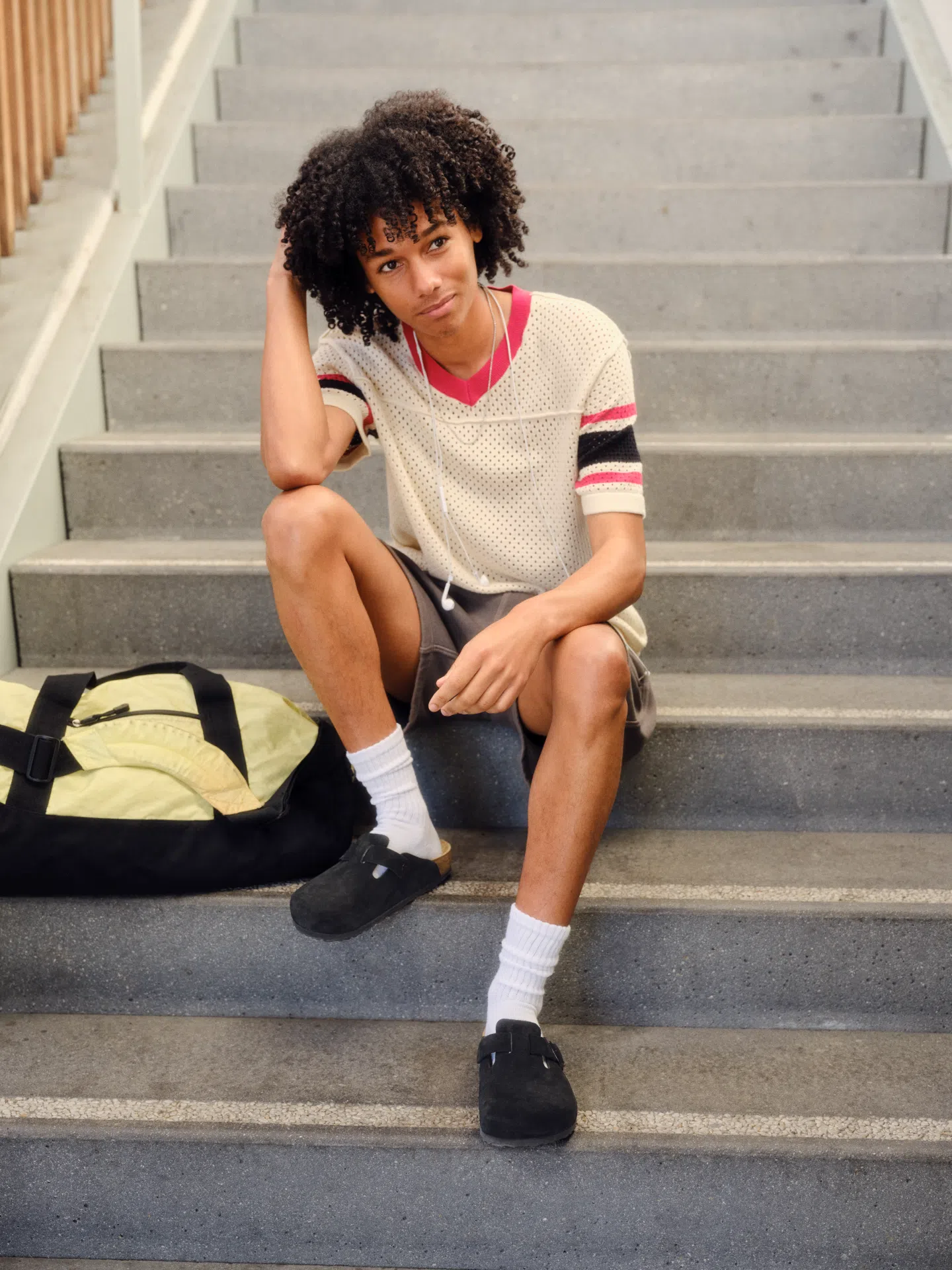 Person wearing Birkenstock Boston Black Suede clogs while sitting on stairs.